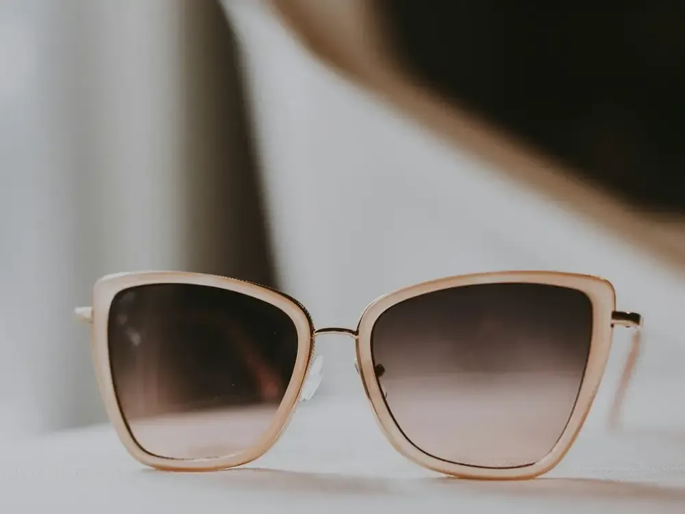 Gafas de sol de montura clara sobre un fondo neutro de estudio